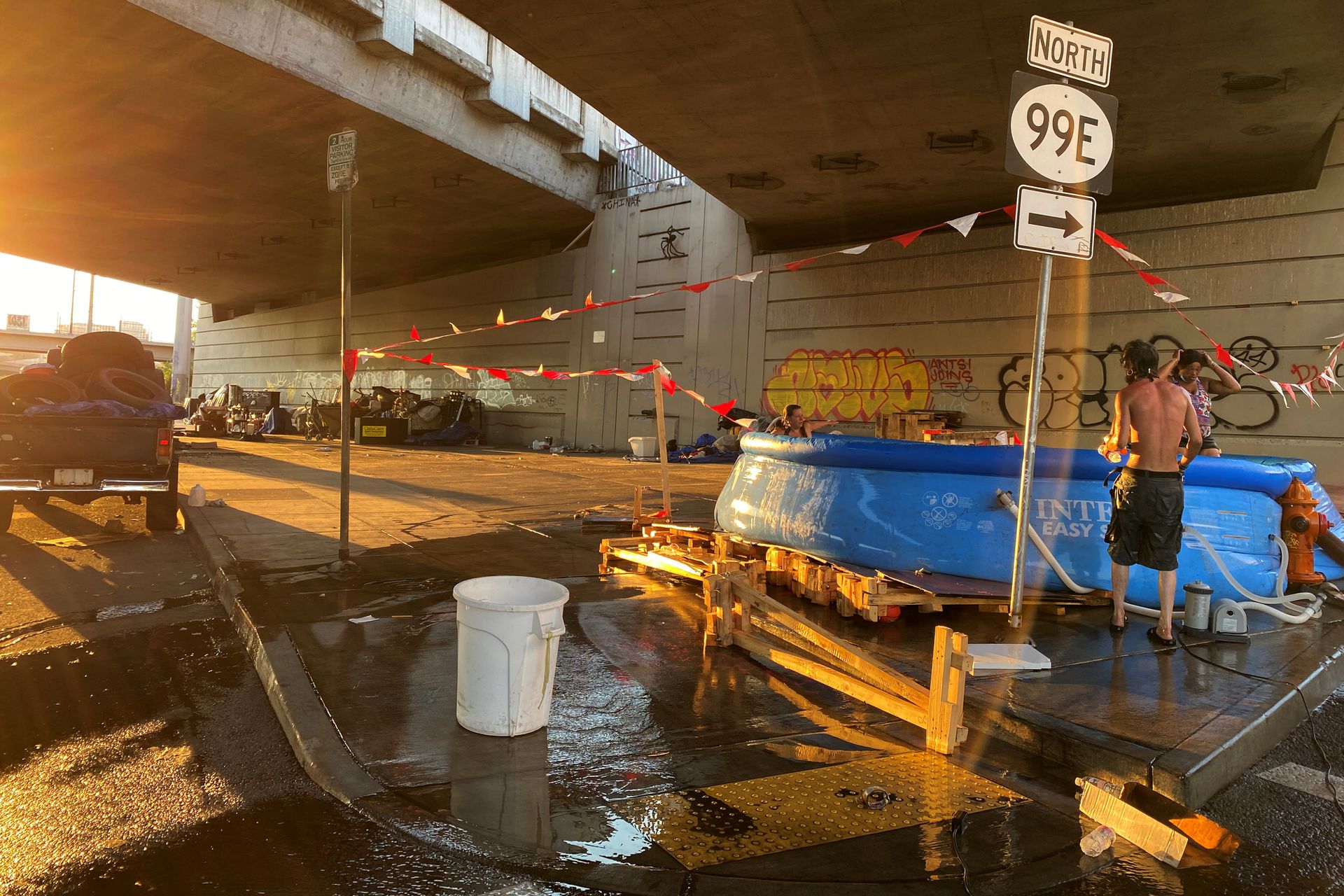 Tyson Morlock stands next to a swimming pool hooked to a fire hydrant under a freeway underpass during a heatwave in Portland, Oregon, U.S., June 29, 2021. Photo: Reuters