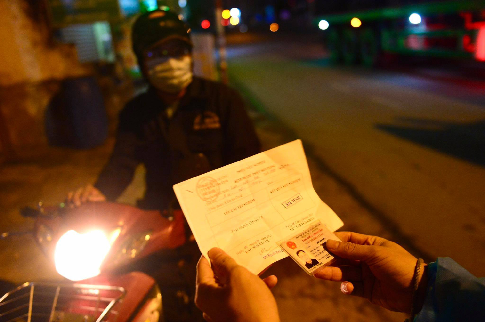 A resident presents his ID and negative COVID-19 test result at a checkpoint in Ho Chi Minh City, July 9, 2021. Photo: Quang Dinh / Tuoi Tre