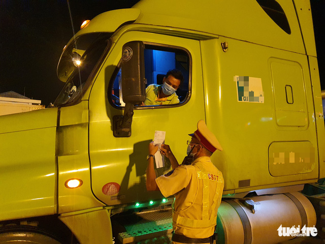 An officer checks a coronavirus-negative certificate belonging to a driver on the Ho Chi Minh City - Long Thanh - Dau Giay Expressway, July 9, 2021. Photo: Minh Hoa / Tuoi Tre