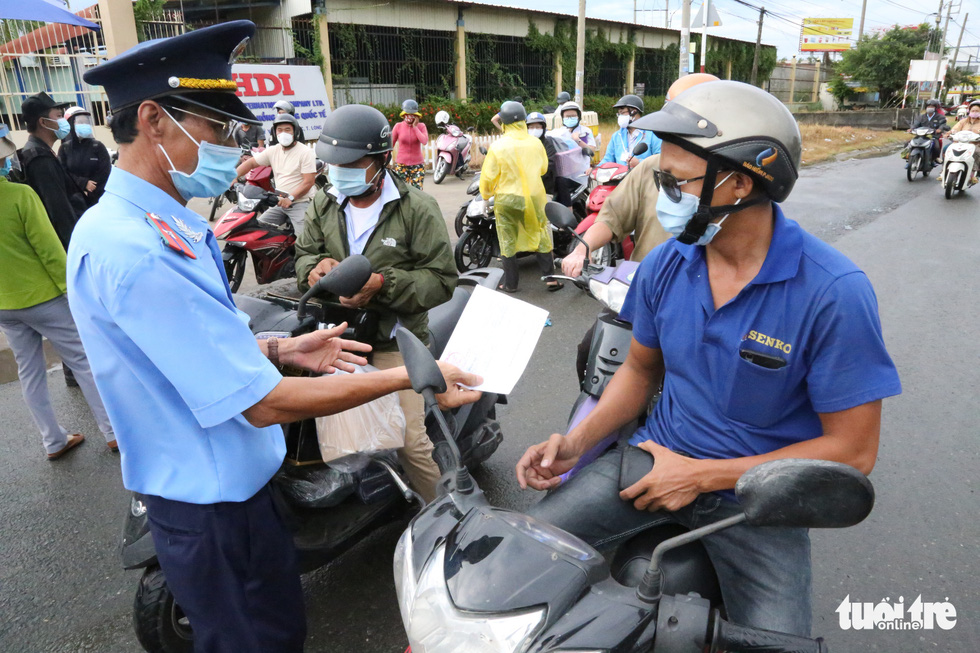 An officer checks a coronavirus-negative certificate belonging to a commuter on National Highway 1, July 8, 2021. Photo: Le Phan / Tuoi Tre