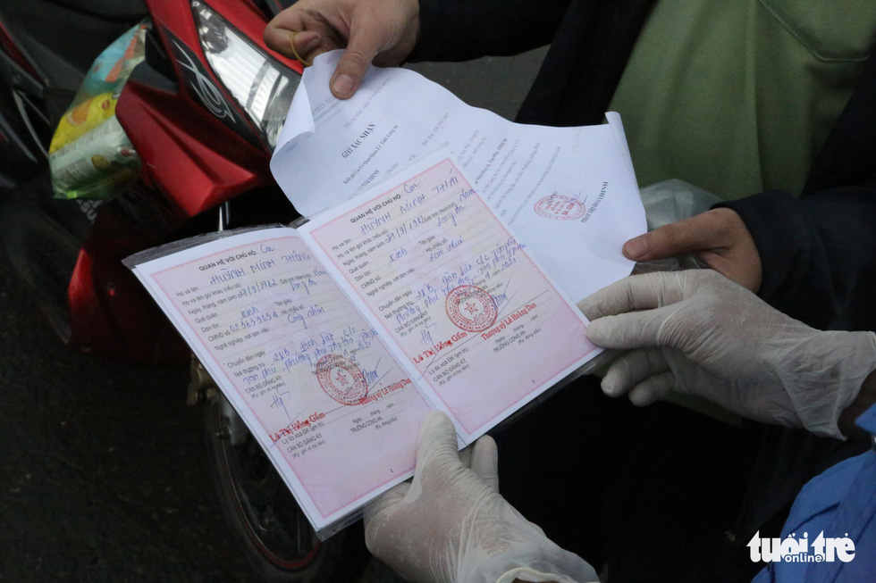 An officer checks a coronavirus-negative certificate belonging to a commuter on National Highway 1, July 8, 2021. Photo: Le Phan / Tuoi Tre