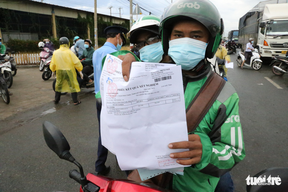 Kim Hanh returns to Ho Chi Minh City to test for COVID-19 and shows the virus-free certificate to officers at a medical checkpoint on National Highway 1 to continue his trip to Soc Trang Province, July 8, 2021. Photo: Le Phan / Tuoi Tre