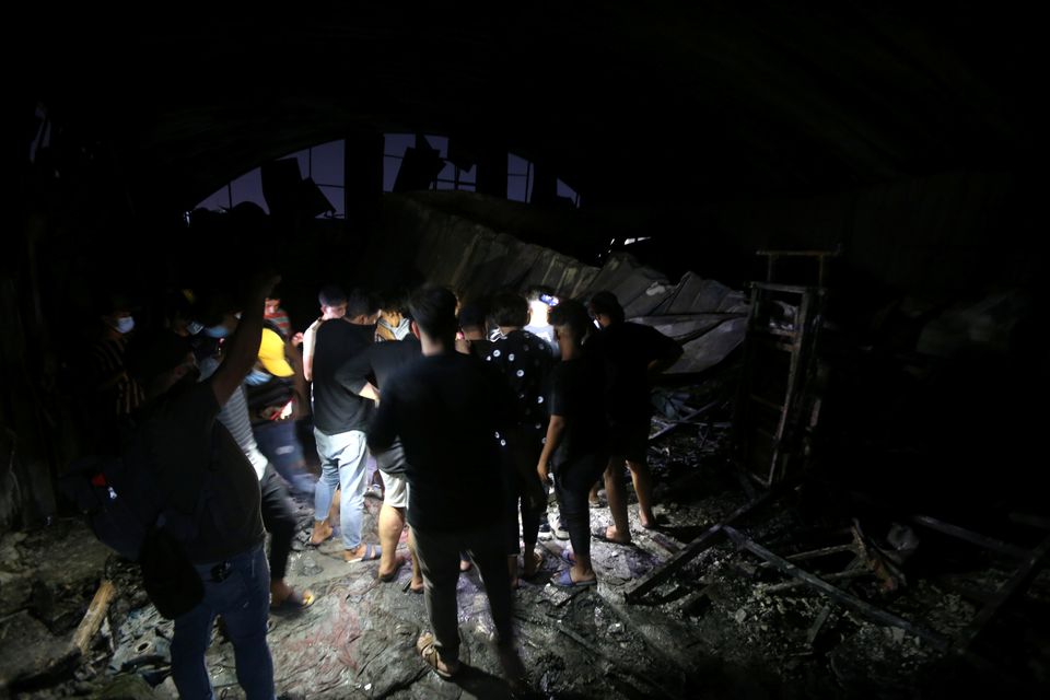 People inspect the damage at the site where a fire broke out at al-Hussain coronavirus hospital, in Nassiriya, Iraq, July 13, 2021. Photo: Reuters