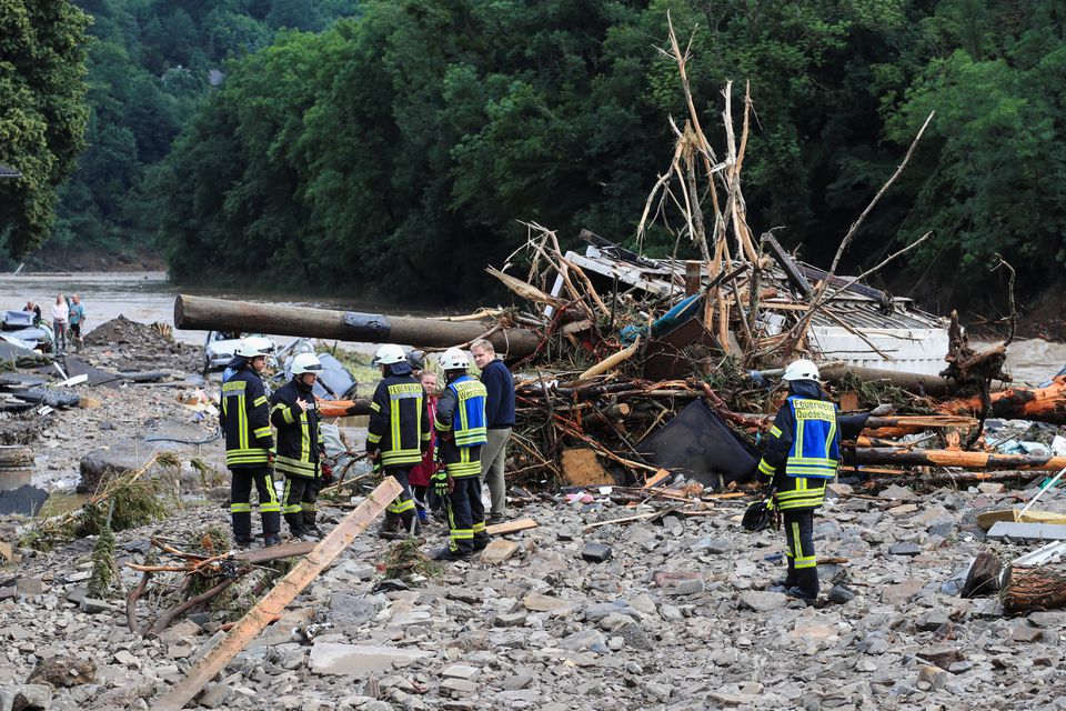 Firefighters speak with people next to debris brought by the flood following heavy rainfalls in Schuld, Germany, on July 15, 2021. Photo: Reuters