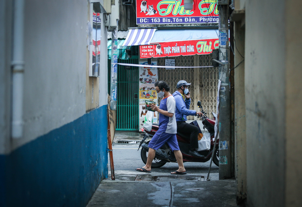 Residents walking on Ton Dan Street, District 4 fetch bags of necessities during the elevated social distancing mandate in Ho Chi Minh City. Photo: Chau Tuan / Tuoi Tre