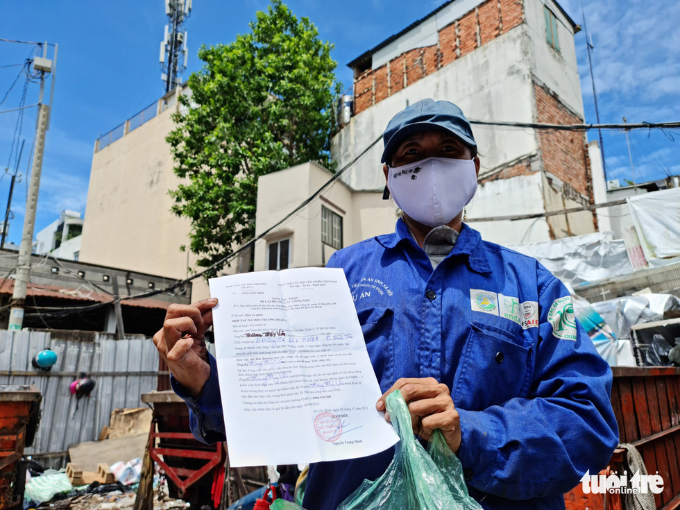 Le Van Phuc shows a paper proving his essential worker status during the pandemic. Photo: Cong Trieu / Tuoi Tre