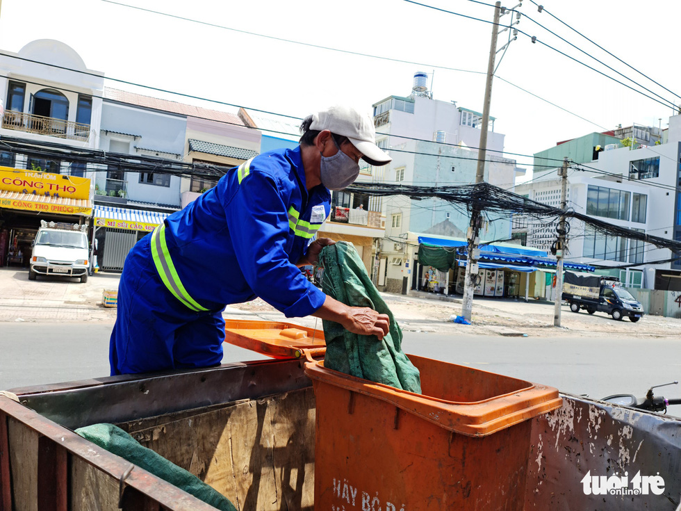 Le Van Phuc, 51, a sanitation worker in Ho Chi Minh City, takes out the trash. Photo: Cong Trieu / Tuoi Tre