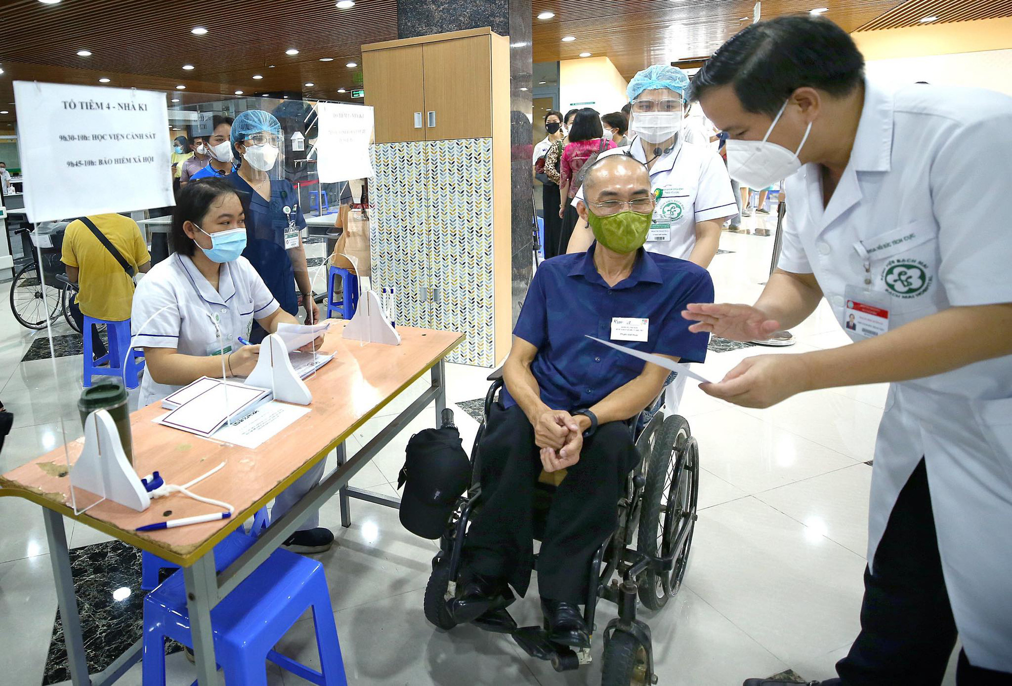 A staff member assists a disabled worker with paperwork before a COVID-19 vaccination session in Hanoi, July 29, 2021. Photo: Ministry of Planning and Investment