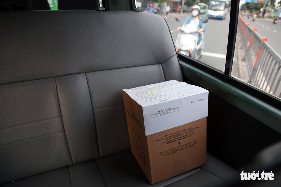 A box of ashes of a COVID-19 victim in Ho Chi Minh City is placed on the backseat of a car. Photo: Le Phan / Tuoi Tre