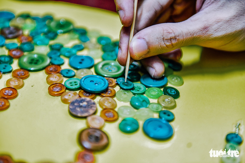 Nguyen Phuoc Quy Thanh create a piece of art using a variety of buttons and beads. Photo: Ngoc Phuong / Tuoi Tre News