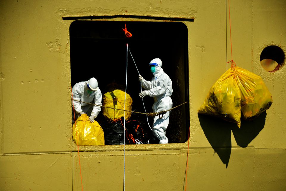 Workers wearing personal protective equipment (PPE) unload trash from a passenger ship owned by the state-owned shipping company PT PELNI, KM Umsini, which has been modified into an isolation centre for the coronavirus disease (COVID-19) patients in Makassar, South Sulawesi province, Indonesia, August 8, 2021, in this photo taken August 8, 2021 by Antara Foto. Antara Foto/Abriawan Abhe/ via Reuters