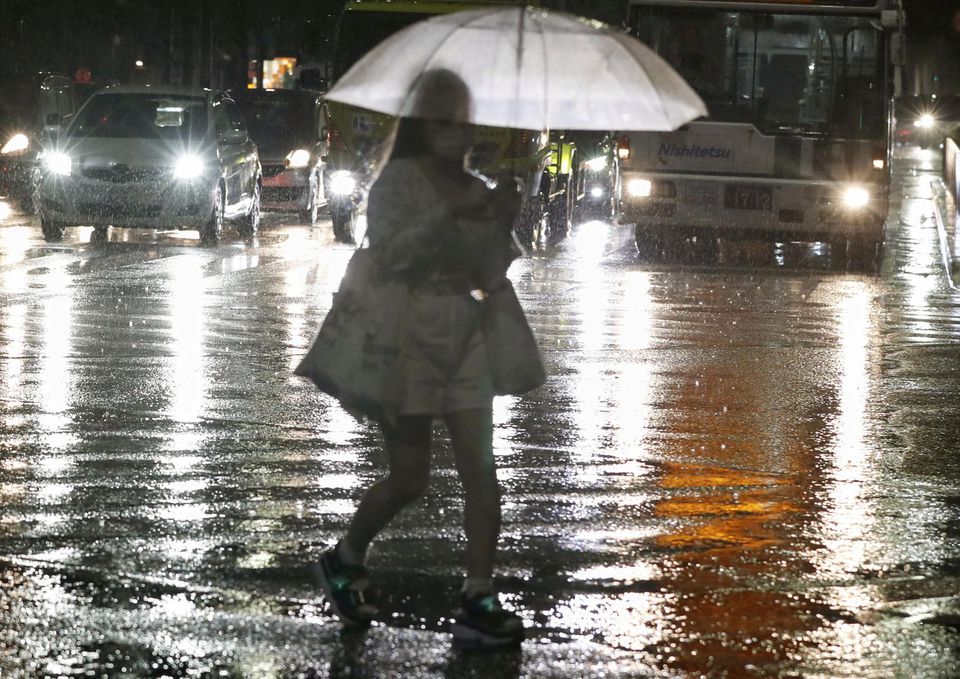 A passerby holding an umbrella walks in the heavy rain in Fukuoka, southwestern Japan August 12, 2021, in this photo taken by Kyodo. Picture taken by Kyodo. Mandatory credit Kyodo/via Reuters