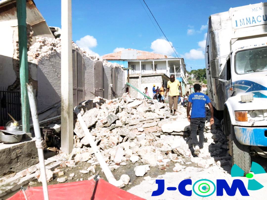 People walk through debris following an earthquake in Jeremie, Haiti August 14, 2021, in this picture obtained from social media. Courtesy of Twitter @JCOMHaiti/ via Reuters