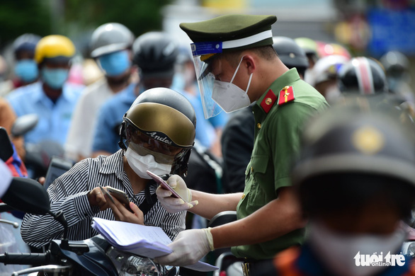 A police officer in Ho Chi Minh City guides a motorbike rider on how to complete health declaration, August 14, 2021. Photo: M.H. / Tuoi Tre