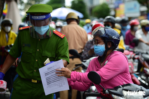 A police officer in Ho Chi Minh City guides a motorbike rider on how to complete health declaration, August 14, 2021. Photo: M.H. / Tuoi Tre