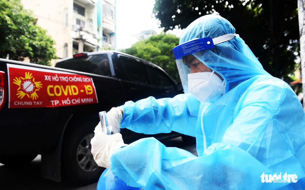Huynh Quang Nhat Long wears a pair of surgical gloves to protect himself before driving his car carrying free oxygen cylinders to COVID-19 patients in the city. Photo: Duyen Phan / Tuoi Tre News