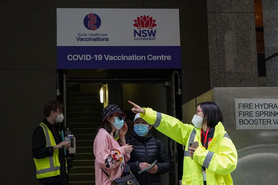 A staff member speaks with people at the entrance to a vaccination centre as a lockdown remains in place to curb the spread of a coronavirus disease (COVID-19) outbreak in Sydney, Australia, August 18, 2021. Photo: Reuters