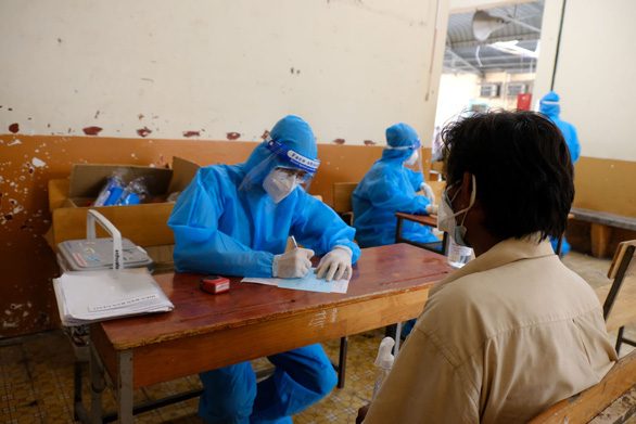 Medical officers perform health screening before inoculating a homeless person against COVID-19 at a shelter in District 4 of Ho Chi Minh City. Photo: Vu Thuy / Tuoi Tre