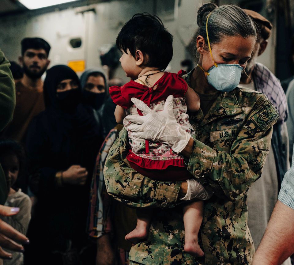 Naval Air Station Sigonella Command Master Chief Anna Wood carries an Afghanistan evacuee off a U.S. Air Force C- 17 Globemaster lll at Naval Air Station Sigonella, August 22, 2021. U.S. Photo: Marine Corps/Sgt. William Chockey/Handout via Reuters