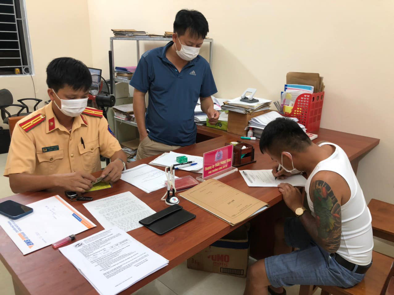 L.V.T. (right) fills out a police record after being found hiding in the trunk of a car in Son Duong District, Tuyen Quang Province, Vietnam, August 30, 2021. Photo: Tran Hong Quang / Tuoi Tre