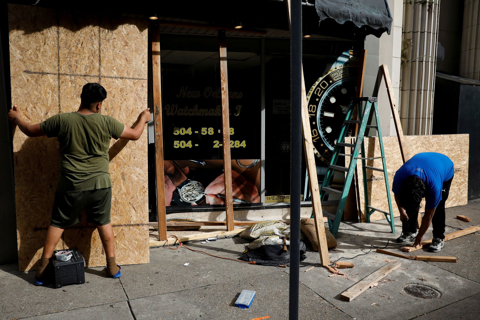 Men place plywood in front of a store in preparation for Hurricane Ida, in New Orleans, Louisiana, U.S. August 28, 2021. Photo: Reuters