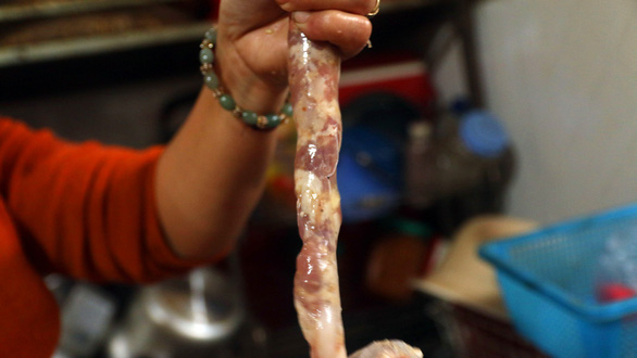 Meat filling is stuffed into the pig's intestine to make lap xuong sausage. Photo: Dao Tho / Tuoi Tre