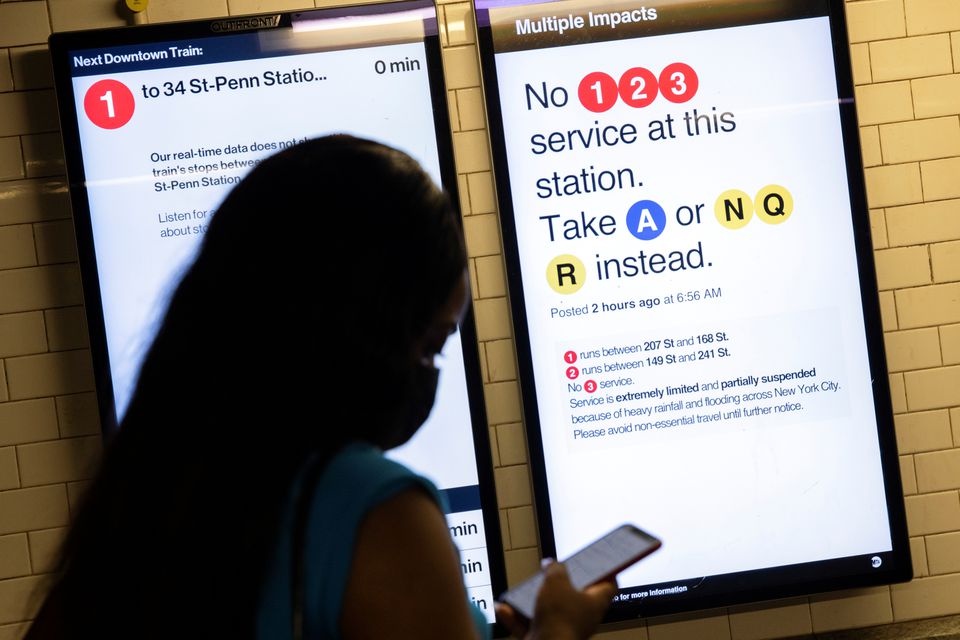 A commuter checks her phone with signs warning of delays caused by heavy rainfall and flooding in the New York City subway after the remnants of Tropical Storm Ida brought drenching rain and the threat of flash floods to parts of the northern mid-Atlantic, in New York City, U.S., September 2, 2021.  Photo: Reuters