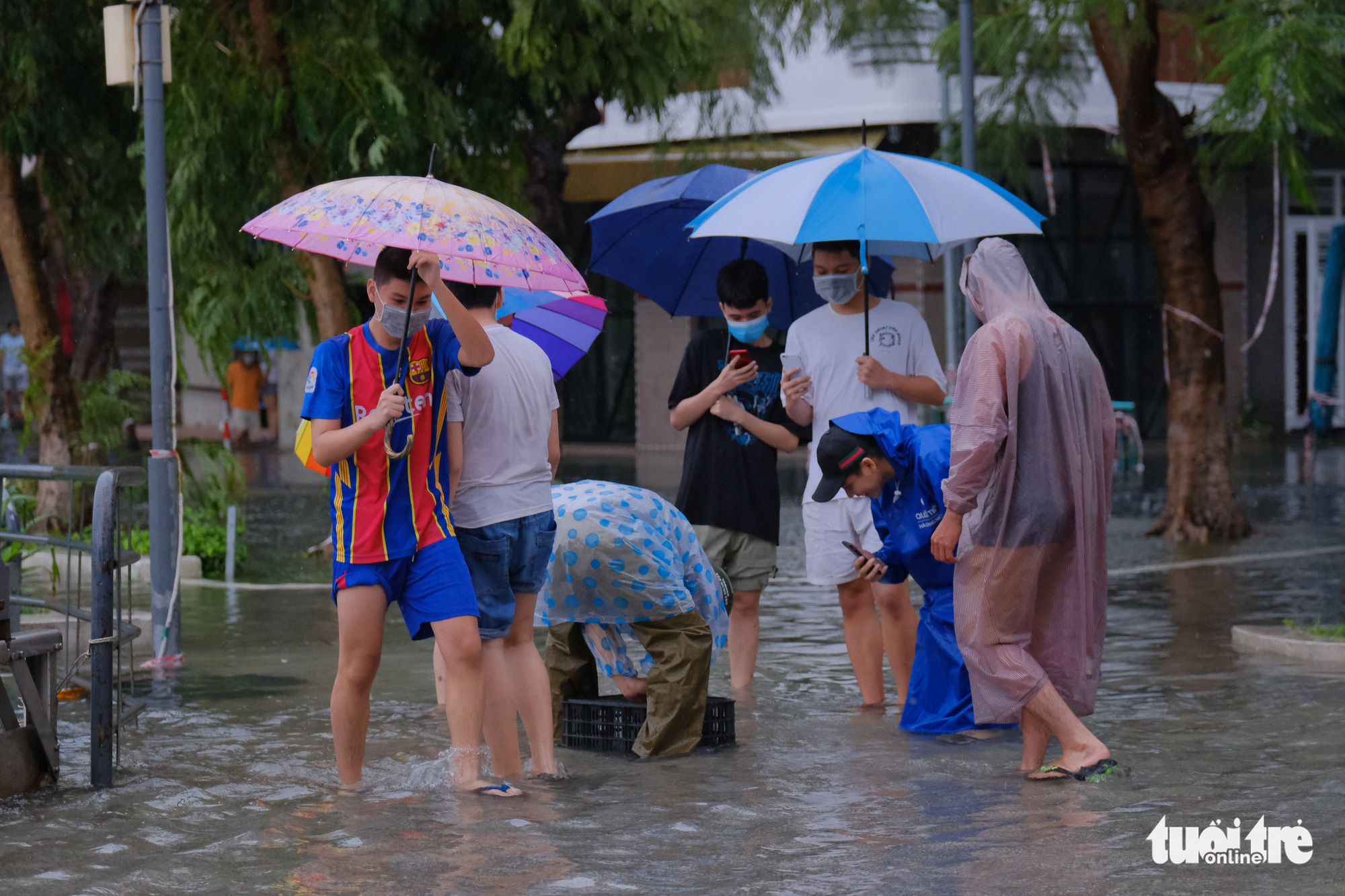 Youngsters use smartphones filming a man catching fish with a plastic cage on the flooded Ham Nghi Street in Da Nang City, Vietnam, September 12, 2021. Photo: Tan Luc / Tuoi Tre
