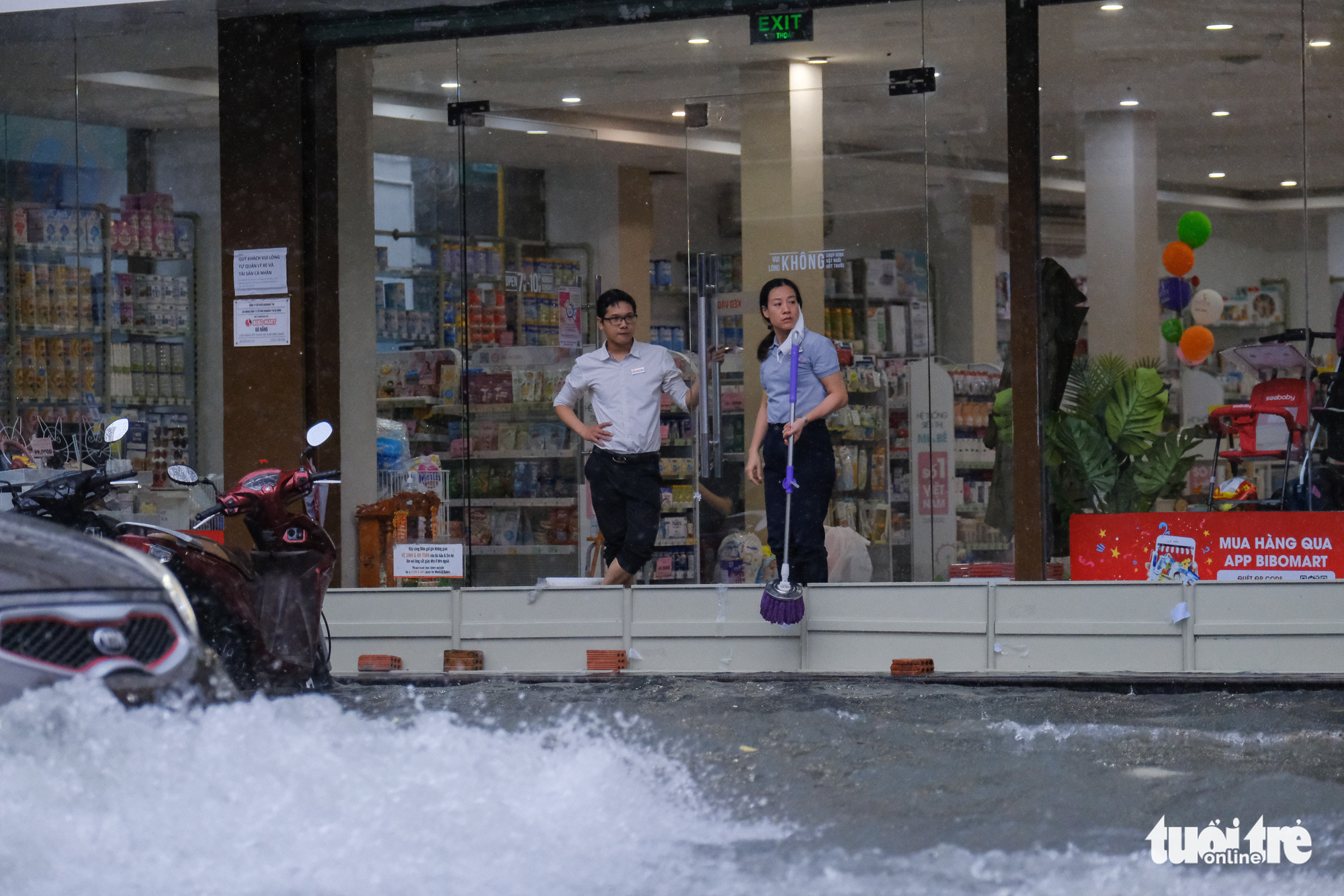 Employees at a mother and baby care shop install a metal shield to block rainwater from pouring into the facility on Hung Vuong Street in Da Nang City, Vietnam, September 12, 2021. Photo: Tan Luc / Tuoi Tre