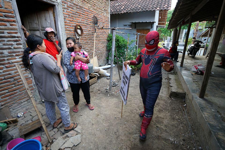 Agus Widanarko, 40, wears a Spiderman costume while carrying a sign as he entertains children confined to their homes due to coronavirus disease (COVID-19) restrictions, in Sukoharjo, Central Java province, Indonesia, September 10, 2021. Photo: Reuters