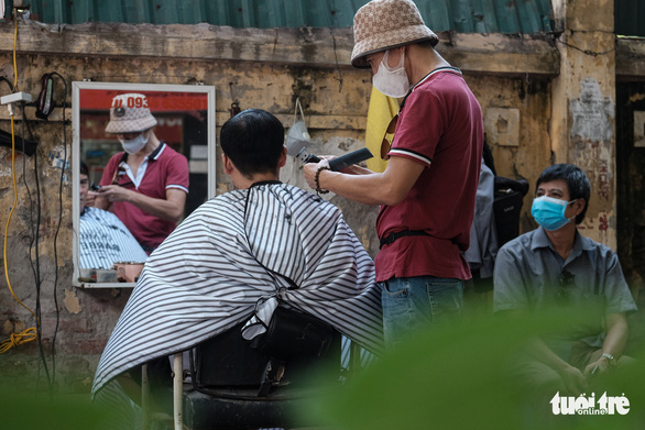 A resident gets a haircut at a street barbershop on Thai Thinh Street, Dong Da District, Hanoi, September 21, 2021. Photo: Mai Thuong / Tuoi Tre