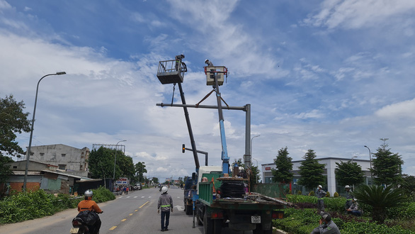 Workers removes a traffic light pole to make way for the 200-year-old banyan tree to leave downtown Quang Ngai City, Quang Ngai Province, Vietnam, September 25, 2021. Photo: Tran Mai / Tuoi Tre