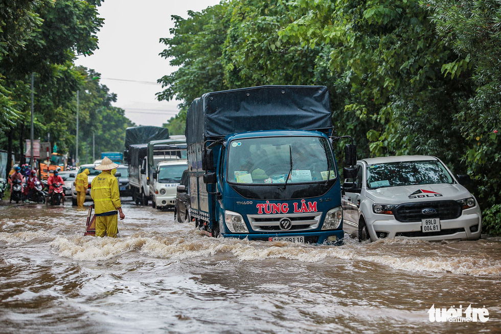 Trucks drive through flooding in Hanoi, Vietnam, October 11, 2021. Photo: Nam Tran / Tuoi Tre