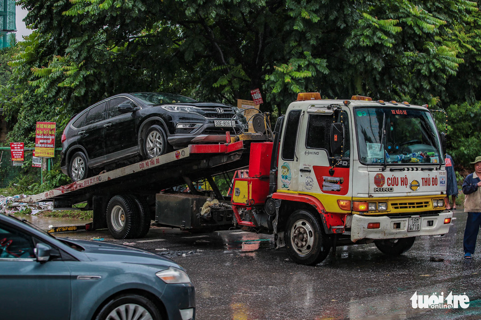 Broken-down cars are towed off a flooded street in Hanoi, October 11, 2021. Photo: Nam Tran / Tuoi Tre