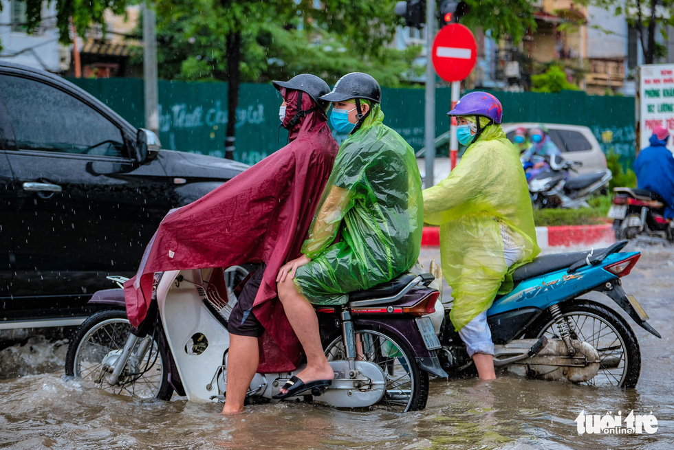 A motorbike travels through flooding on the To Huu - Luong The Vinh intersection in Nam Tu Liem District, Hanoi, Vietnam, October 11, 2021. Photo: Nam Tran / Tuoi Tre