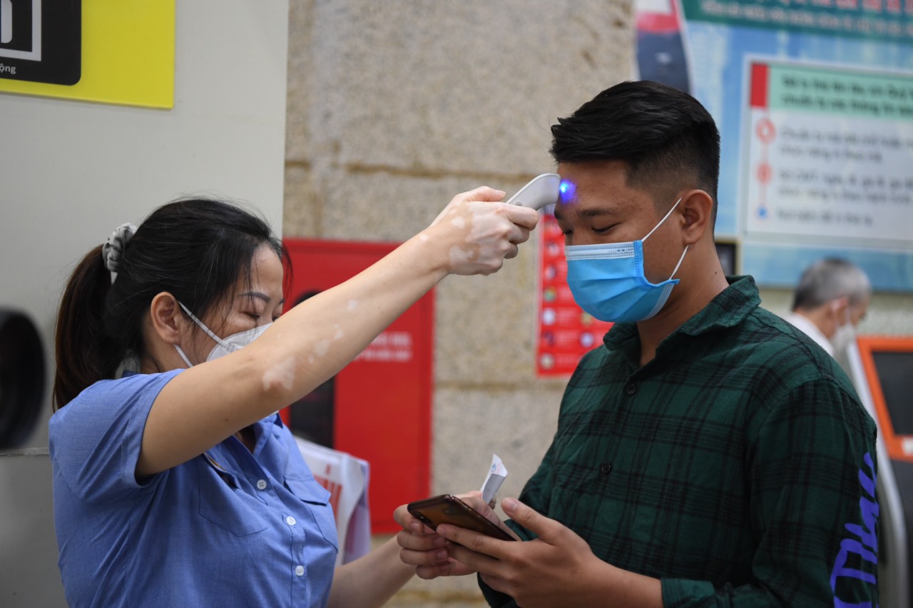 A passenger has his body temperature measured at Hanoi Railway Station, October 13, 2021. Photo: Duy Hoang / Tuoi Tre