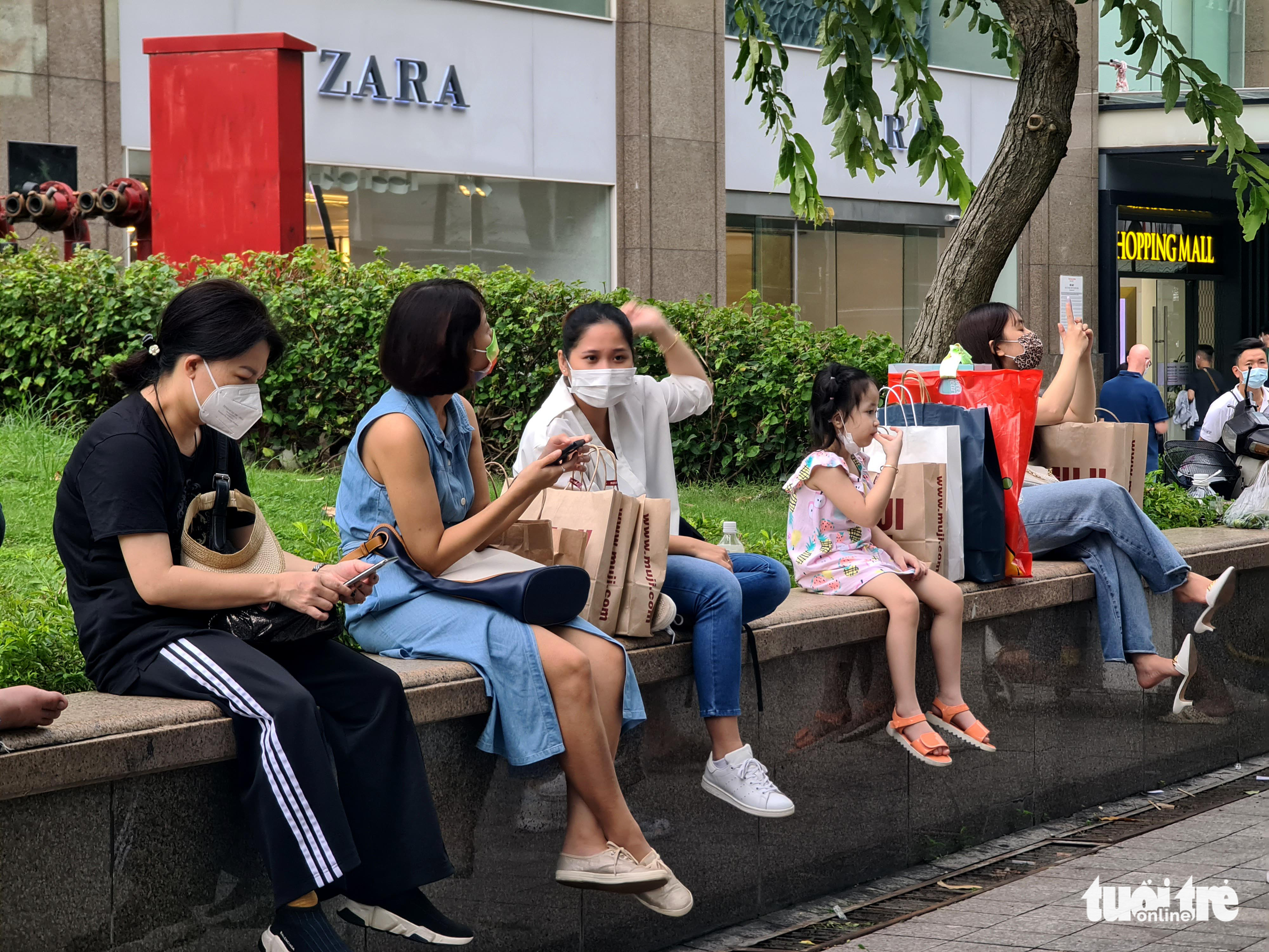 Shoppers take a break on the sidewalk in front of a shopping mall in District 1, Ho Chi Minh City, October 16, 2021. Photo: Ngoc Hien / Tuoi Tre