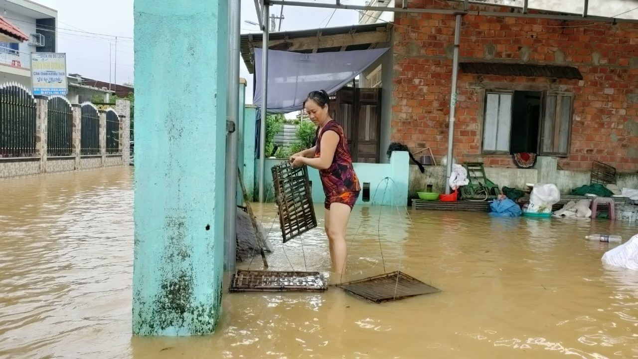 A woman stands inside her flooded house in Quang Nam Province. Photo: Duc Tai / Tuoi Tre