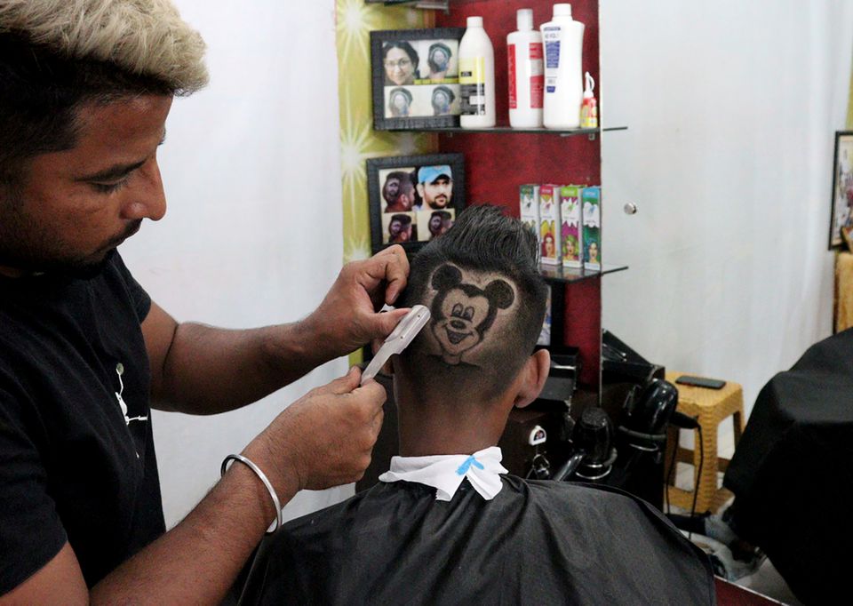 Rajwinder Singh Sidhu, 29, a barber, shaves the hair of a customer in the shape of Mickey Mouse inside his shop in Dabwali town, in the northern state of Punjab, India, October 12, 2021. Photo: Reuters