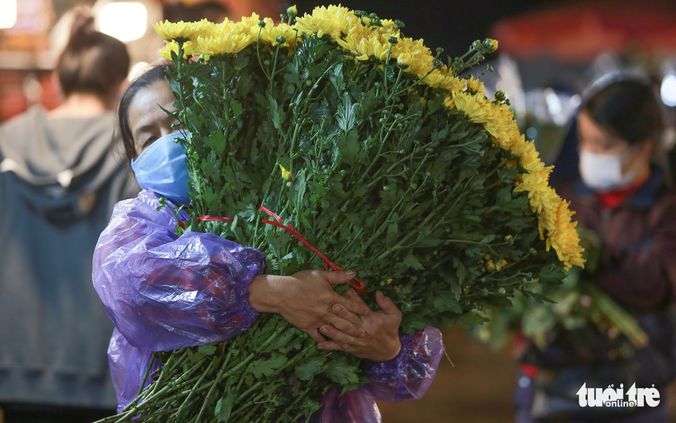 A woman carries a bunch of flowers at a flower market ahead of Vietnamese Women's Day (October 20) in Hanoi. Photo: Tuoi Tre