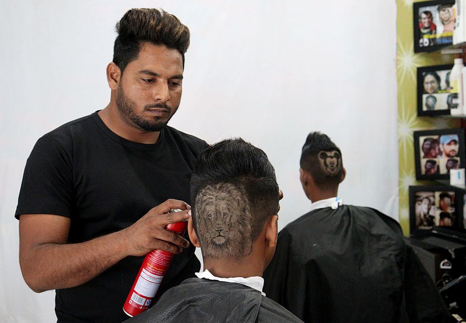 Gurwinder Singh Sidhu, 31, a barber, gives the finishing touches to the hair of a customer after making a hair tattoo in the shape of a lion on his head inside their shop in Dabwali town, in the northern state of Punjab, India, October 12, 2021. Photo: Reuters