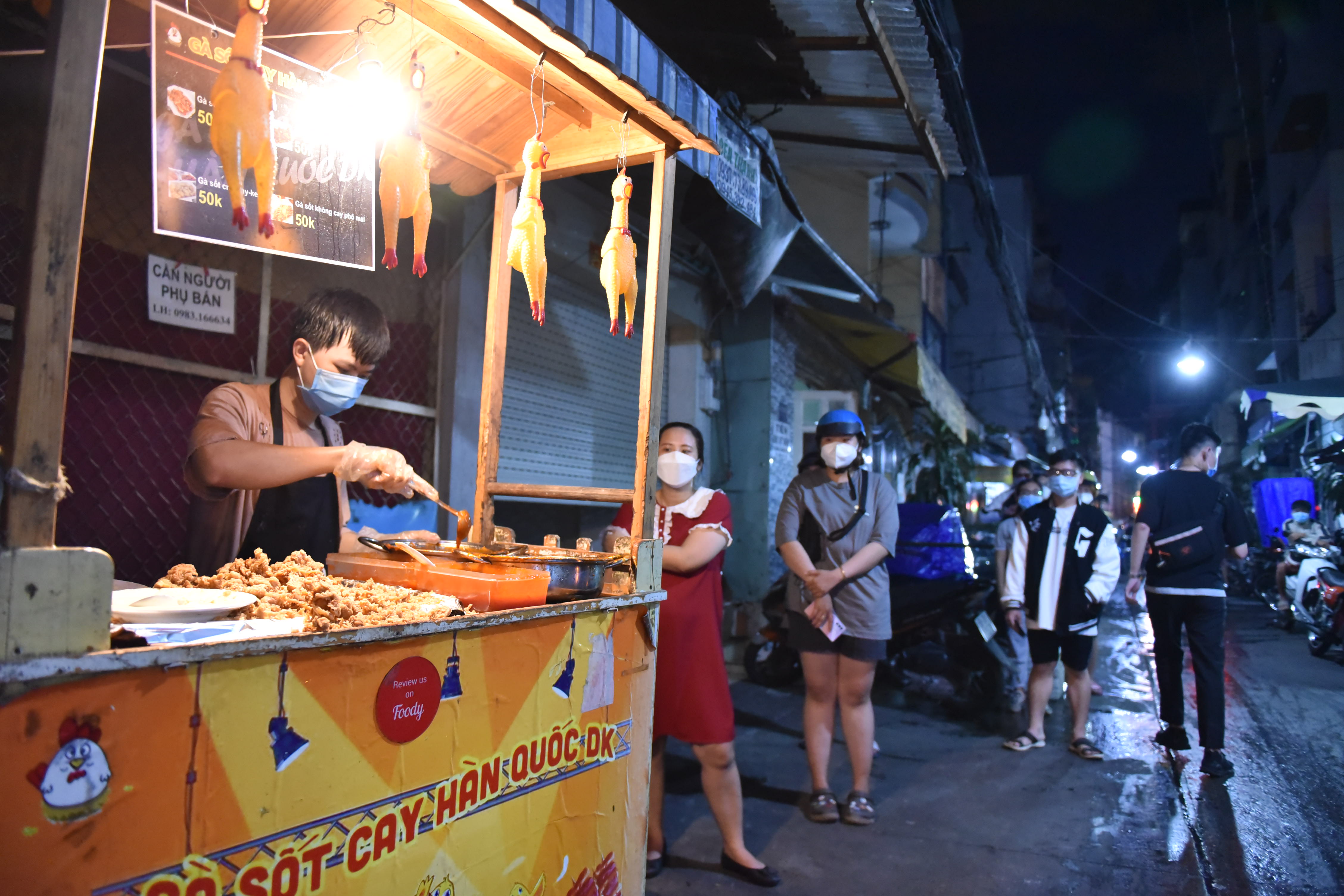 Customers wait in line for their Korean spicy chicken at a stall at Ho Thi Ky Food Street in Ho Chi Minh City’s District 10 on October 19, 2021. Photo: Ngoc Phuong / Tuoi Tre