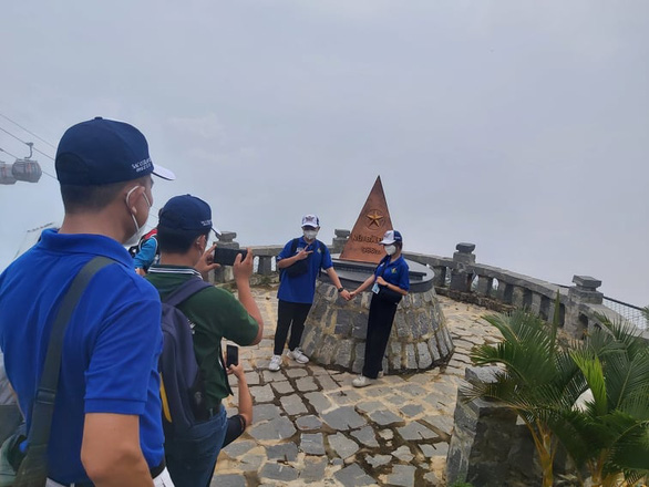 Visitors pose for photo at a milestone atop Be Den Mountain in the southern province of Tay Ninh on October 18, 2021. Photo: Nhu Binh / Tuoi Tre