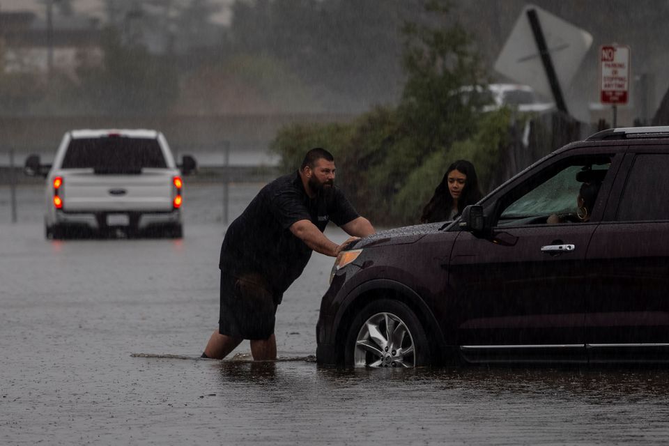 A couple pushes a vehicle away from a flooded area as a powerful storm drenched northern California in Fairfield, California, U.S. October 24, 2021. Photo: Reuters