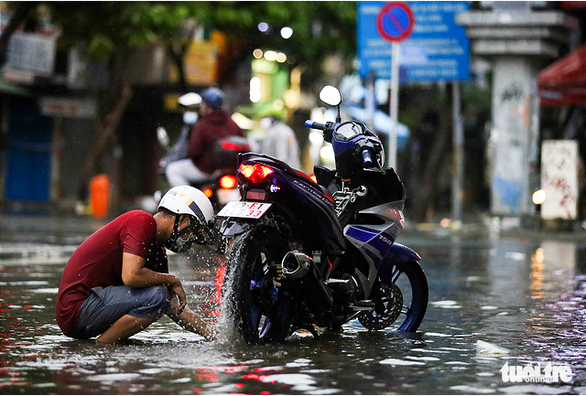A motorcyclist tries to fix his motorbike in the midst of floodwater in District 1, Ho Chi Minh City. October 24, 2021. Photo: Le Phan / Tuoi Tre