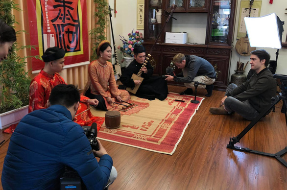 François Bibonne (right) sits with a group of artists performing Chau van - Vietnamese ritual singing while he makes his film in a supplied photo.