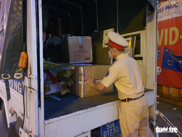 A traffic police officer loads boxes of items onto a truck following the removal of the COVID-19 checkpoint at Song Than overpass on National Highway 1A in Ho Chi Minh City, October 26, 2021. Photo: Minh Hoa / Tuoi Tre