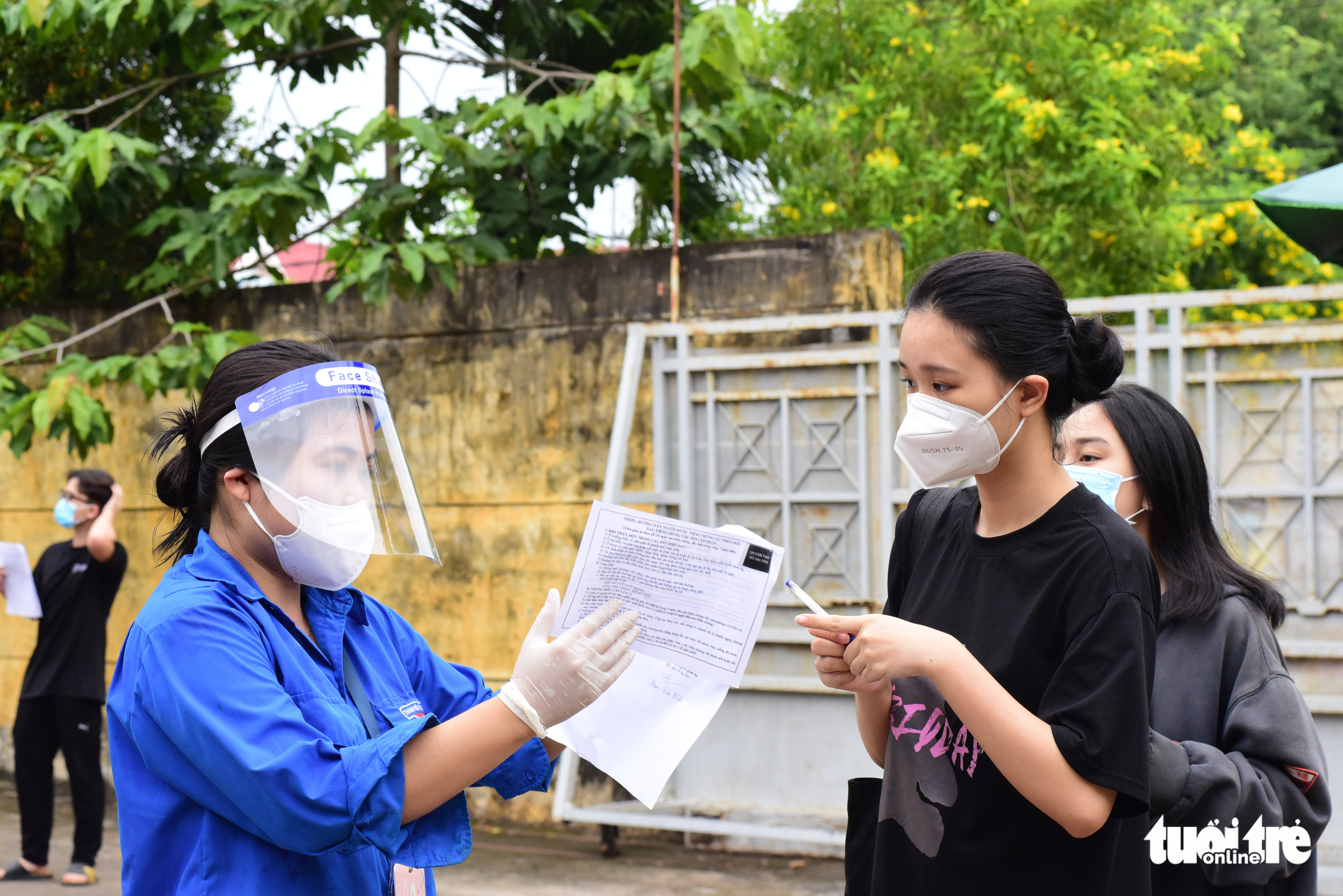 A volunteer helps students file health declarations prior to their vaccination in Cu Chi District, Ho Chi Minh City, October 27, 2021. Photo: Duyen Phan / Tuoi Tre