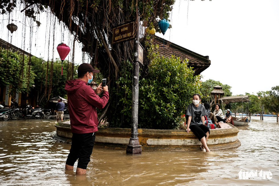 A woman poses for a photo on a flooded corner in Hoi An Ancient Town, Quang Nam Province, Vietnam, October 24, 2021. Photo: Tan Luc / Tuoi Tre