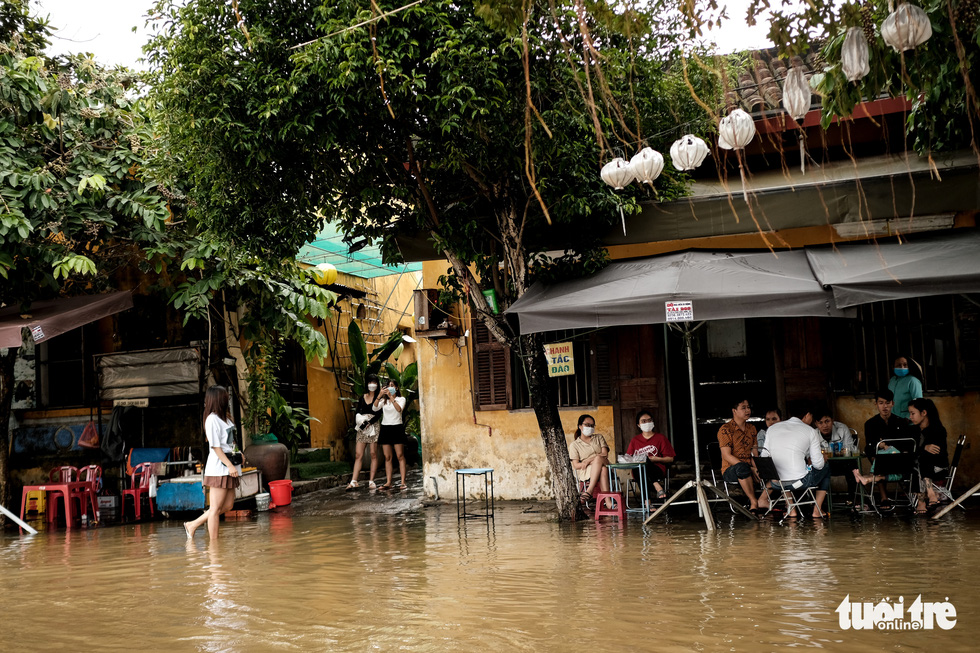 Tourists snap photos and sip coffee at a flooded café in Hoi An Ancient Town, Quang Nam Province, Vietnam, October 24, 2021. Photo: Tan Luc / Tuoi Tre